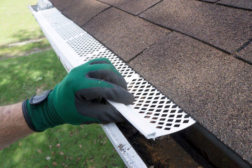 A man installing leaf filter on the roof gutter